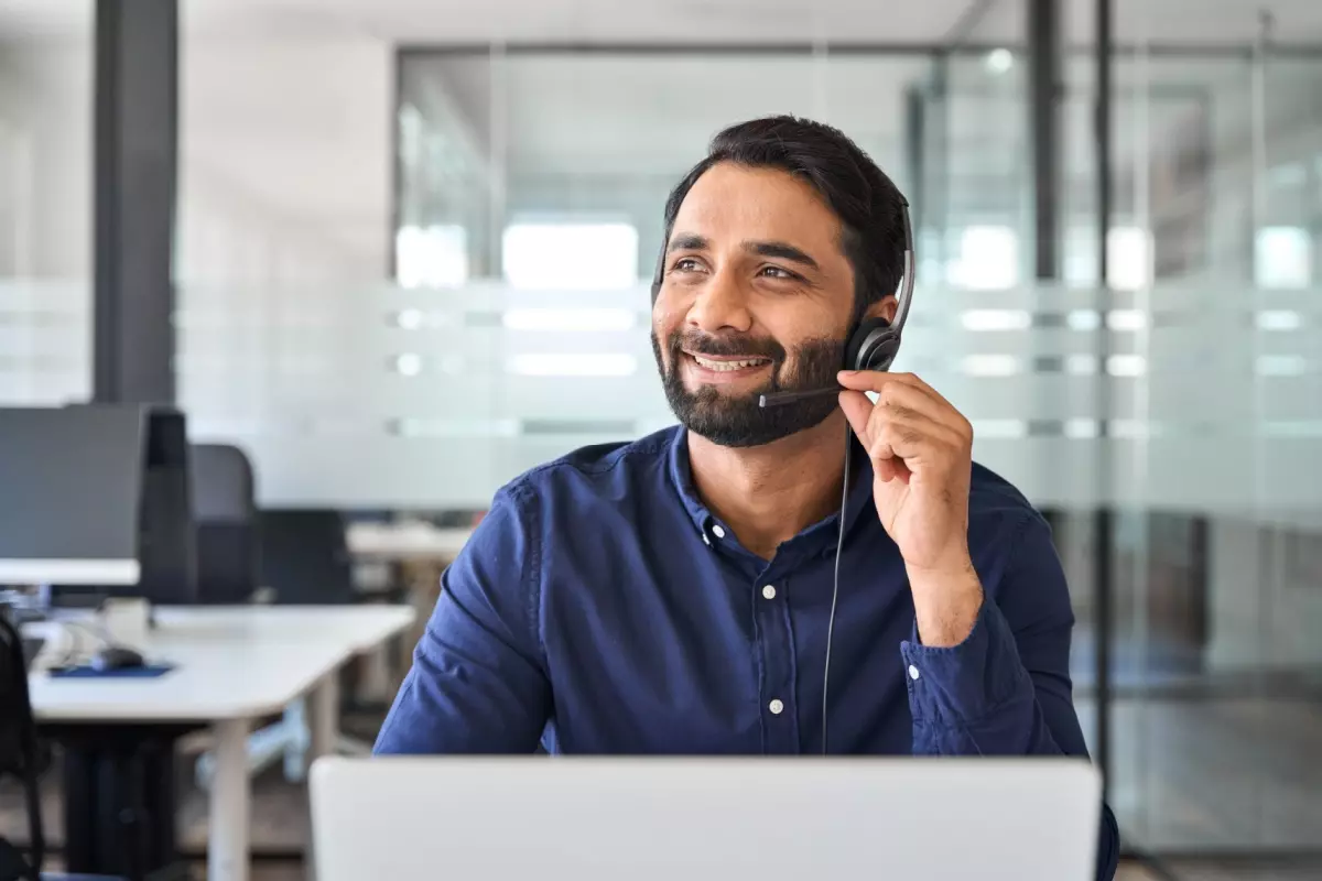 Smiling customer support agent talking on the phone with headphones.